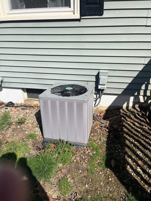 Completed full AC system retrofit including outdoor condenser unit and indoor air handler replacement. Installed new condenser unit on exterior pad adjacent to light green siding with proper clearances, mounted electrical disconnect box on exterior wall, and ran conduit connections to unit. Interior installation included new air handler in basement utility area with complete PVC condensate drain piping in Y-configuration, insulated supply plenum, flexible return ductwork connections, and refrigerant line set routing between indoor and outdoor units. Verified all electrical connections, tested system startup and operation, and confirmed proper drainage flow.