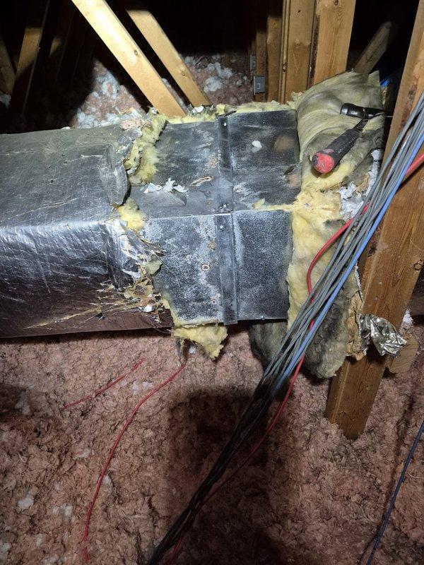 Responded to attic ductwork repair request and found severely deteriorated flexible duct with torn outer vapor barrier and exposed internal insulation causing significant air leakage and energy loss. Removed damaged flexible duct section, installed new properly-sized flexible ductwork with intact insulation and vapor barrier, secured all connections with mastic and metal straps per code requirements, and supplemented attic floor insulation with additional pink fiberglass batts to restore proper R-value and thermal efficiency.