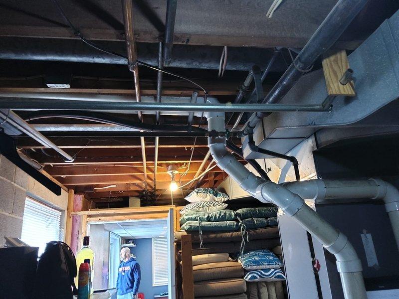 Completed furnace retrofit in basement mechanical room. Assessed existing HVAC system configuration including air handler unit, ductwork, and piping infrastructure to determine optimal replacement approach. Documented pre-installation conditions showing existing equipment layout, exposed ceiling joists with insulated ductwork, copper piping, and structural clearances required for new furnace installation and proper ventilation routing.