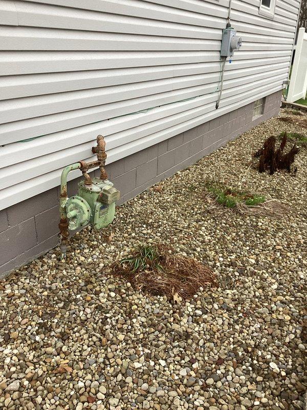 Conducted site evaluation for installation of 8-foot gas line to support new standby generator. Assessed existing gas meter and utility infrastructure, including current piping configuration and connection points. Documented site conditions showing weathered gas meter assembly with corroded piping and valve connections mounted on concrete foundation. Evaluated gravel bed work area and exterior wall access points along vinyl siding for optimal routing of new gas line. Provided comprehensive estimate for gas line installation, including materials and labor requirements for safe connection from existing gas meter to proposed generator location.