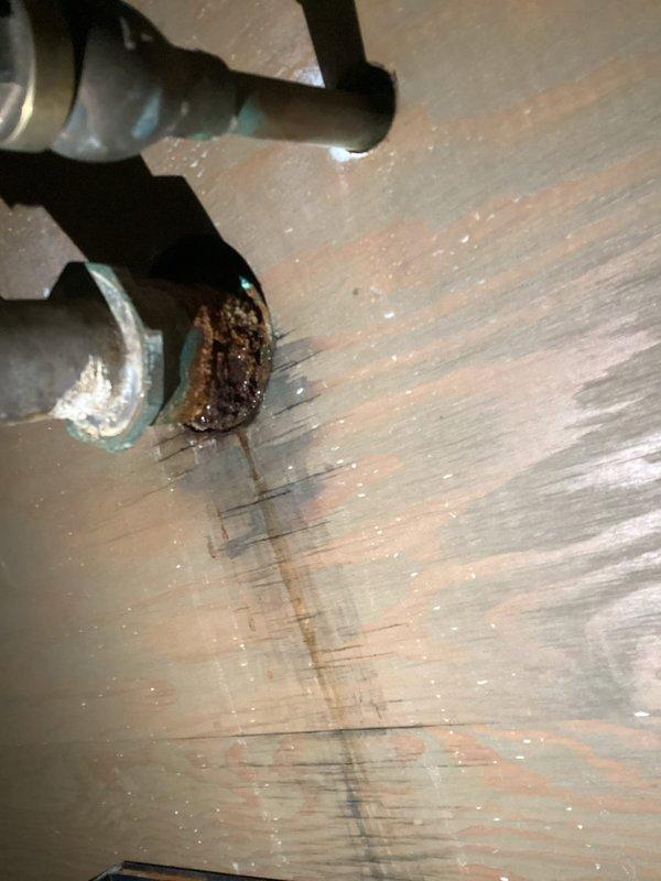 Responded to a service call for a clogged drain and water leak in a utility room break area. Upon inspection, identified significant corrosion and rust buildup on threaded pipe connections beneath the sink cabinet, with visible copper oxidation and mineral deposits indicating long-term moisture exposure. Cleared the drain blockage and addressed the leaking connection, which had caused water staining on the surrounding wooden surfaces. Documented the corroded plumbing infrastructure and completed necessary repairs to restore proper drainage and eliminate the active leak.