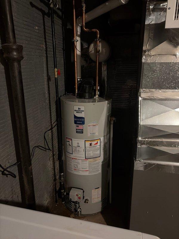 Completed installation of new gray metal furnace unit in basement mechanical room. Connected white PVC piping for condensate drainage and exhaust venting, integrated unit with existing gray insulated ductwork system overhead, and verified proper electrical connections. All equipment tested and confirmed operational upon completion.