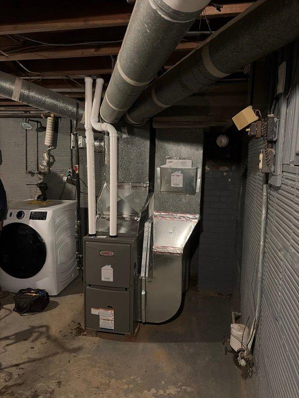 Completed installation of new gray metal furnace unit in basement mechanical room. Connected white PVC piping for condensate drainage and exhaust venting, integrated unit with existing gray insulated ductwork system overhead, and verified proper electrical connections. All equipment tested and confirmed operational upon completion.