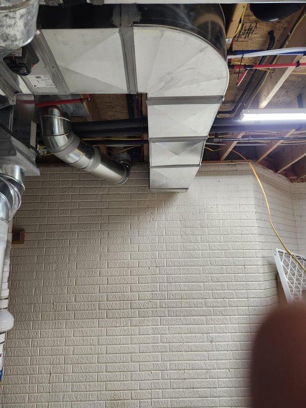 Completed new construction HVAC installation including air handler unit mounted in attic space with metallic flex ductwork and rigid metal supply distribution system. Installed vertical supply trunk lines in basement mechanical room with polished metal ductwork connecting to horizontal air handler, integrated electrical junction box with conduit routing, and coordinated installation with existing water heating equipment and PVC drain lines. All ductwork properly sealed and secured to framing, insulation installed between wall studs, and system staged for final connections and startup upon completion of construction phase.