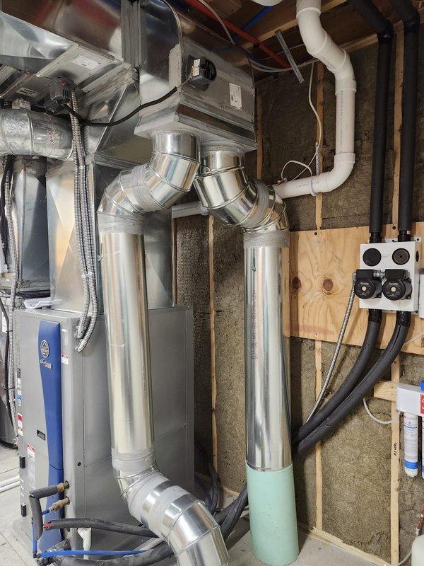 Completed new construction HVAC installation including air handler unit mounted in attic space with metallic flex ductwork and rigid metal supply distribution system. Installed vertical supply trunk lines in basement mechanical room with polished metal ductwork connecting to horizontal air handler, integrated electrical junction box with conduit routing, and coordinated installation with existing water heating equipment and PVC drain lines. All ductwork properly sealed and secured to framing, insulation installed between wall studs, and system staged for final connections and startup upon completion of construction phase.