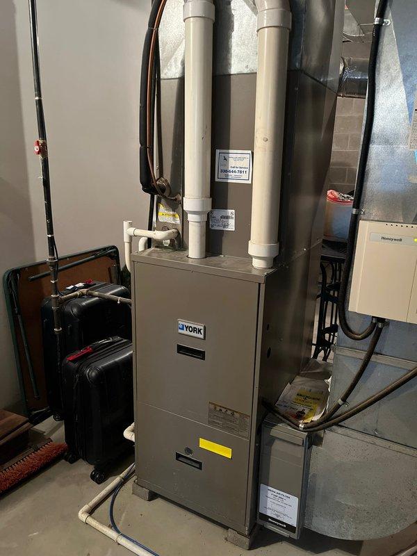 Completed full HVAC system replacement including installation of new York furnace in basement utility room and matching York condenser unit on exterior concrete pad. Installed PVC intake and exhaust venting from furnace through ceiling, ran copper refrigerant lines with insulation connecting indoor and outdoor units, and mounted electrical disconnect box with conduit routing to house electrical system. All ductwork connections, electrical wiring, and control systems properly configured and tested for operation.