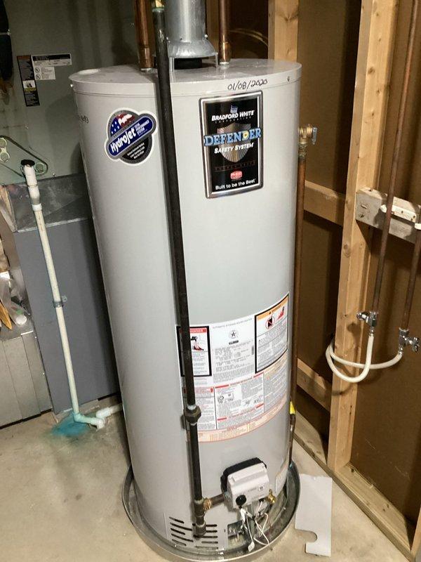 Responded to emergency service call for leaking tanked water heater. Upon arrival, inspected Bradford White Defender Safety System unit installed in 2020 and identified active leak originating from top connections. Evaluated copper piping connections, flue pipe assembly, and overall tank condition to determine source of water intrusion. Assessed whether repair was viable or replacement would be necessary based on leak severity and unit age. Documented existing installation with photographs showing water heater positioning, plumbing connections, venting configuration, and surrounding utility space layout for service records.