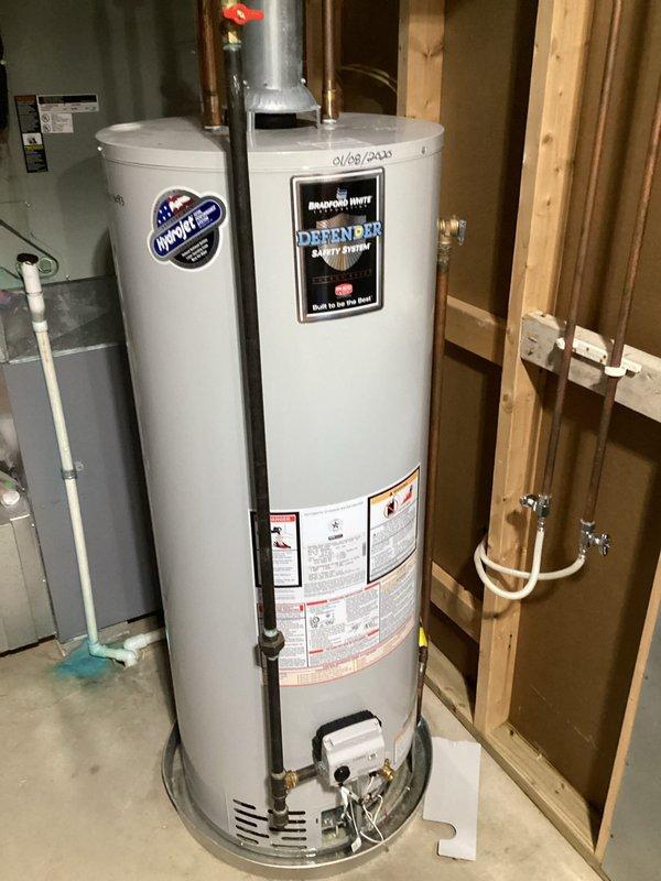 Responded to emergency service call for leaking tanked water heater. Upon arrival, inspected Bradford White Defender Safety System unit installed in 2020 and identified active leak originating from top connections. Evaluated copper piping connections, flue pipe assembly, and overall tank condition to determine source of water intrusion. Assessed whether repair was viable or replacement would be necessary based on leak severity and unit age. Documented existing installation with photographs showing water heater positioning, plumbing connections, venting configuration, and surrounding utility space layout for service records.