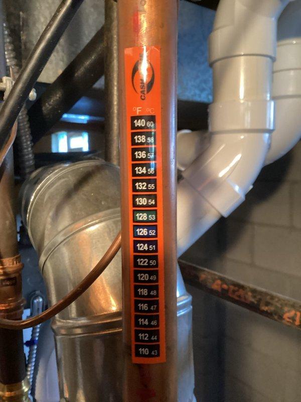 Responded to callback for persistent leak issue. Upon arrival, inspected water heater and associated piping system. Examined temperature and pressure relief valve, copper supply lines, and PVC drain connections. Photographed temperature gauge reading on copper pipe showing system operating temperature between 110-140 degrees. Inspected internal components through access port, noting condition of heating elements, sensors, and electrical connections. Identified source of continued leak at connection point. Tightened fittings, replaced faulty gasket, and tested system under pressure to verify repair completed successfully with no further leakage detected.