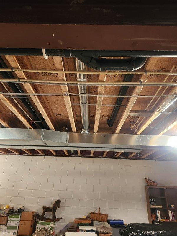 Installed new branch duct from existing trunk line to supply conditioned air to bathroom toe kick register. Routed rigid galvanized ductwork vertically through floor joists and secured with metal strapping to structural members. Terminated duct connection at toe kick location on left side of cabinet as specified, ensuring proper airflow delivery to space. All ductwork properly supported and sealed at connections.