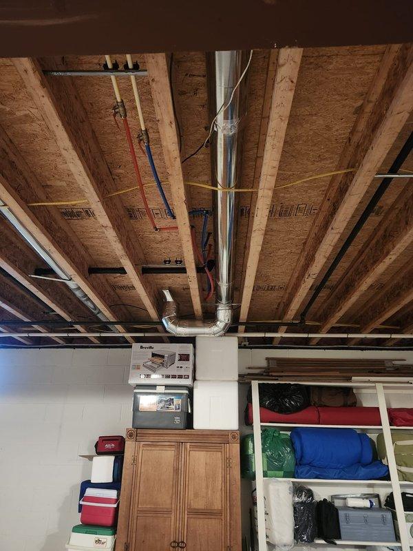 Installed new branch duct from existing trunk line to supply conditioned air to bathroom toe kick register. Routed rigid galvanized ductwork vertically through floor joists and secured with metal strapping to structural members. Terminated duct connection at toe kick location on left side of cabinet as specified, ensuring proper airflow delivery to space. All ductwork properly supported and sealed at connections.