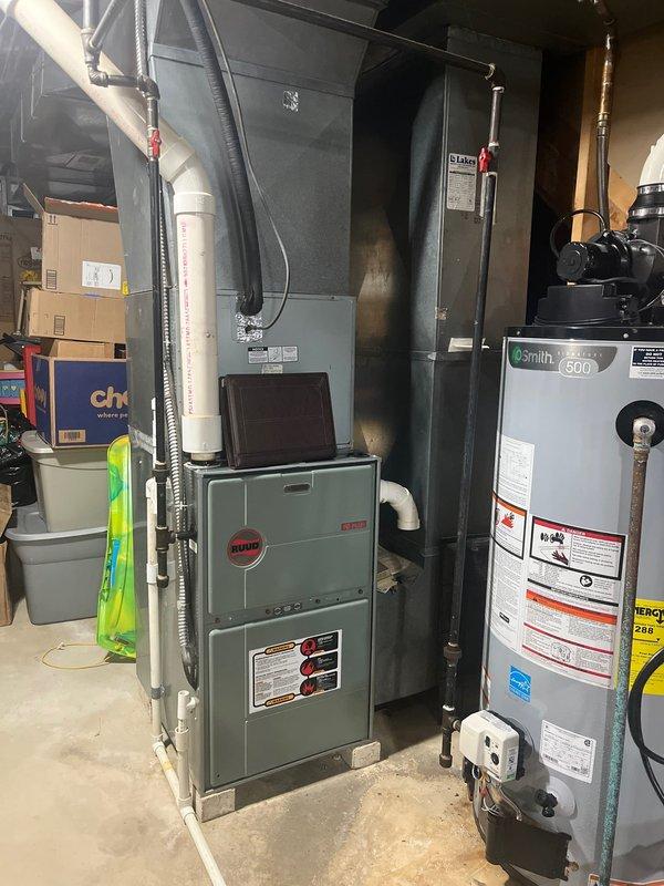 Completed full HVAC system replacement in residential basement utility area, installing new Bryant furnace and air conditioning system. Removed existing equipment and installed new furnace unit with proper venting through white PVC condensate drainage system, connected to overhead ductwork plenum with appropriate flexible metal duct connections. All manufacturer specifications, safety labels, and warning stickers properly affixed to equipment per code requirements, electrical conduit and wiring completed to connect system components, and installation verified for proper operation of heating and cooling functions.