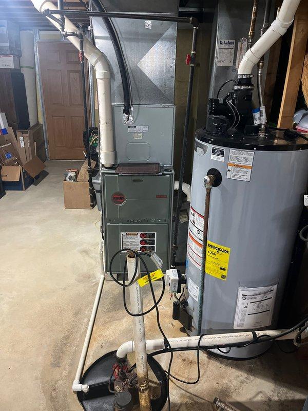 Completed full HVAC system replacement in residential basement utility area, installing new Bryant furnace and air conditioning system. Removed existing equipment and installed new furnace unit with proper venting through white PVC condensate drainage system, connected to overhead ductwork plenum with appropriate flexible metal duct connections. All manufacturer specifications, safety labels, and warning stickers properly affixed to equipment per code requirements, electrical conduit and wiring completed to connect system components, and installation verified for proper operation of heating and cooling functions.