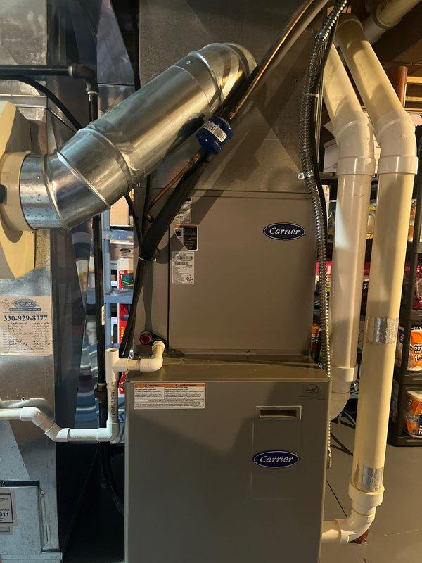 Completed residential AC replacement in garage utility area. Installed new Carrier furnace system with properly configured metallic ductwork, flexible ducting with protective wrapping, and white PVC condensate drainage lines. Connected electrical components to existing breaker panel, ensured proper routing of all ductwork and piping per HVAC standards, and verified system installation on concrete pad with adequate clearances for service access.