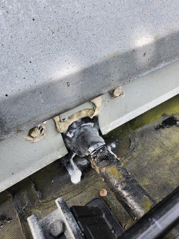 Responded to commercial A/C leak complaint and conducted thorough inspection of rooftop unit and interior ceiling plenum. Located source of water intrusion at rooftop drain assembly with deteriorated connections and inadequate sealing, causing water to migrate through ceiling penetrations where flexible ductwork enters conditioned space. Documented standing water with algae growth around drain fitting, compromised insulation materials, and evidence of chronic moisture exposure on rooftop surface. Identified flexible duct penetration in ceiling grid system as secondary leak point where condensate and rainwater infiltration were entering building interior. Recommended immediate repair of rooftop drainage system, replacement of deteriorated drain fittings and surrounding weatherproofing, cleaning of affected rooftop surfaces to remove biological growth, and proper sealing of all ceiling penetrations around ductwork to prevent future water intrusion.