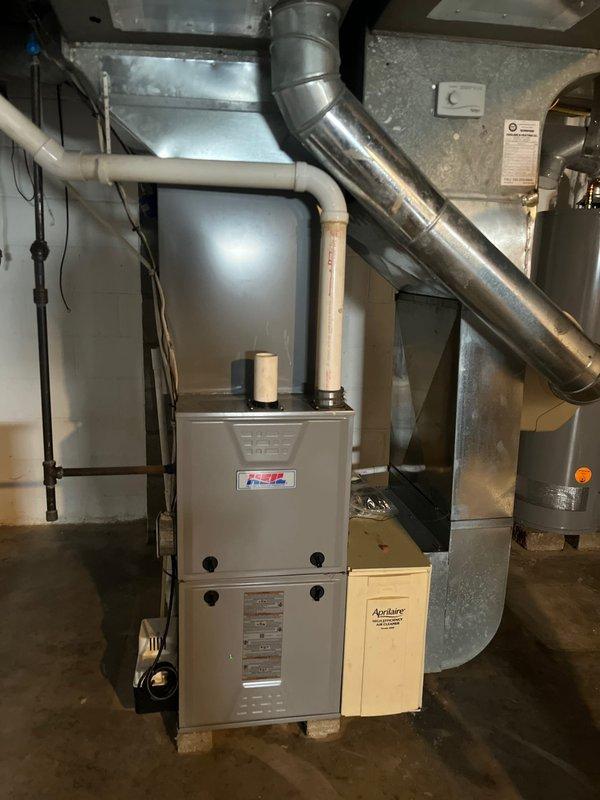 Completed air conditioning retrofit evaluation and comprehensive furnace condition assessment at residential property. Inspected existing HVAC system including beige cabinet-style furnace unit mounted on concrete blocks, verified proper installation of metallic ductwork connections, and examined PVC venting system, electrical conduit, and associated components. Documented current equipment specifications, ductwork configuration, and overall system condition through detailed photography for replacement estimate preparation.