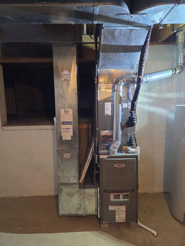 Completed residential air conditioning retrofit installation in basement utility area. Installed new Lennox furnace system with coordinating evaporator coil, integrated with existing ductwork infrastructure. System includes proper condensate drainage using white PVC piping with secure mounting, galvanized sheet metal supply ductwork with vibration isolation components, and black flexible return ducting. All equipment properly positioned against concrete block walls with adequate clearances for service access and code compliance. Installation verified operational with all connections secured and labeled per manufacturer specifications.