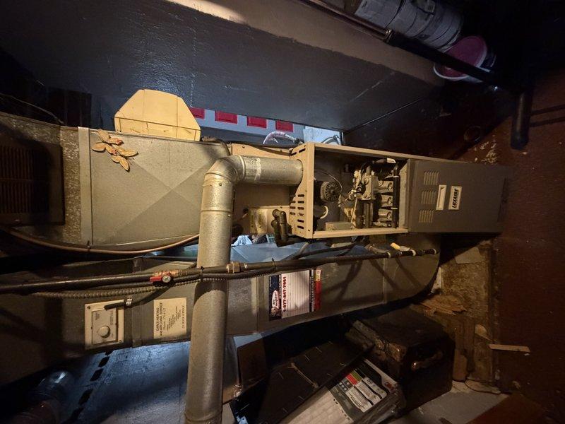 Completed AC retrofit installation including outdoor condenser unit and indoor evaporator coil. Positioned new condenser on existing concrete pad adjacent to building, secured electrical conduit to exterior siding, and connected refrigerant lines. Installed new evaporator coil in basement utility area, integrated with existing furnace system, and connected metallic supply ductwork. Tested system operation, verified proper refrigerant charge, confirmed adequate airflow, and ensured all electrical connections met code requirements. System operational and cooling effectively upon completion.