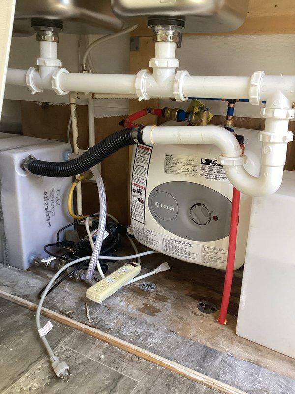 Installed a Bosch compact tankless electric water heater in an under-sink cabinet location within a trailer. Completed all necessary plumbing connections including hot and cold water supply lines with shut-off valves, integrated the unit with existing PVC drain system, and established proper electrical connections to power the unit. The installation was configured to provide on-demand hot water service in a space-constrained environment typical of mobile home applications.