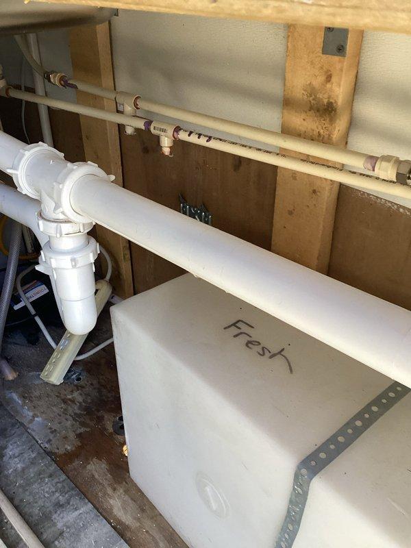 Installed a Bosch compact tankless electric water heater in an under-sink cabinet location within a trailer. Completed all necessary plumbing connections including hot and cold water supply lines with shut-off valves, integrated the unit with existing PVC drain system, and established proper electrical connections to power the unit. The installation was configured to provide on-demand hot water service in a space-constrained environment typical of mobile home applications.