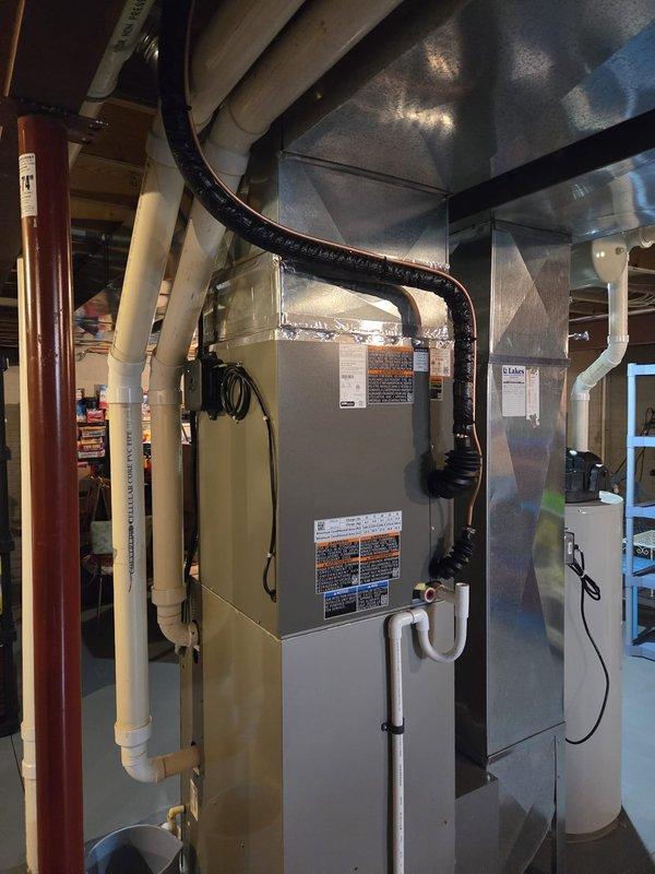 # A/C & Coil Replacement

Completed full air conditioning system replacement including outdoor condensing unit and indoor evaporator coil to restore cooling capacity to residential property. Removed existing failed A/C equipment and installed new Carrier-compatible cooling system matched to existing furnace infrastructure. New evaporator coil was mounted above the furnace in the basement mechanical room with proper refrigerant line connections, condensate drainage routing to existing PVC system, and electrical integration. Outdoor condensing unit was positioned per manufacturer specifications with appropriate clearances and connected via refrigerant linesets. System was evacuated, charged to factory specifications, and tested for proper operation across all cooling modes. Verified adequate airflow, temperature differential, and thermostat communication. All ductwork connections were inspected and sealed as needed to maintain system efficiency. Equipment startup procedures completed suc