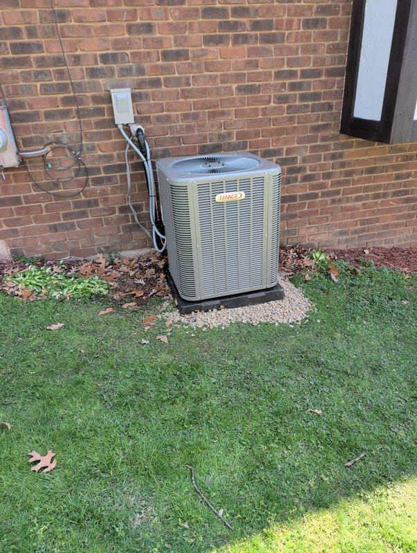Completed full air conditioning system replacement including outdoor condenser unit and indoor evaporator coil. Removed existing equipment and installed new beige residential condenser on concrete pad with proper refrigerant line connections and electrical disconnect box mounted to exterior brick wall. Installed new indoor air handler unit with access panel in mechanical room, connected all ductwork, and verified proper refrigerant charge. System tested and operational upon completion.