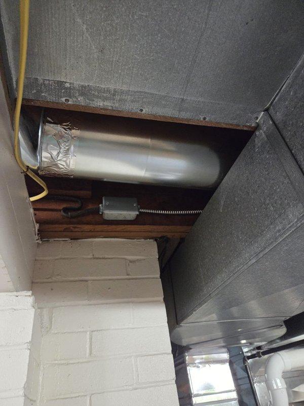 Completed HVAC rough-in ductwork installation for residential renovation project. Installed main trunk line and branch ducts through framed chase opening, including flexible duct connections to distribution points. Exterior condensing unit previously positioned on gravel pad with proper electrical disconnect and conduit routing in place.