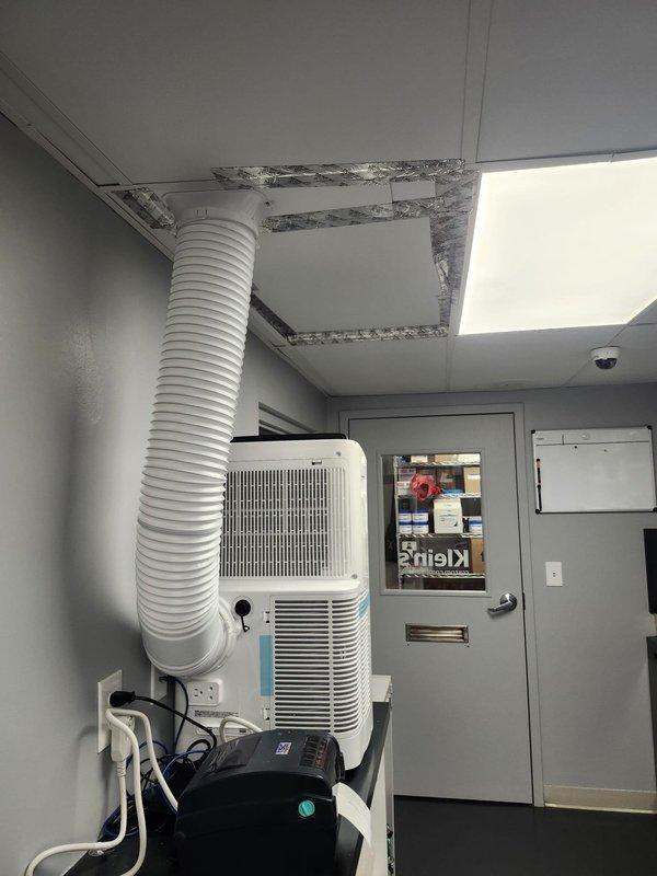 Responded to water leak service call and documented temporary cooling solution in place. Portable air conditioning unit installed with flexible exhaust duct routed through modified ceiling tile opening, sealed with reflective foil tape to maintain proper ventilation and prevent air leakage.
