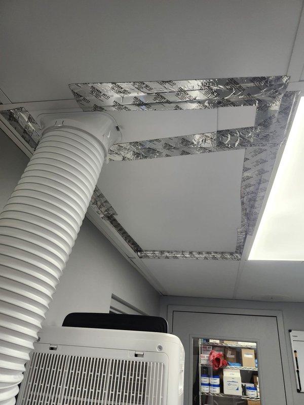 Responded to water leak service call and documented temporary cooling solution in place. Portable air conditioning unit installed with flexible exhaust duct routed through modified ceiling tile opening, sealed with reflective foil tape to maintain proper ventilation and prevent air leakage.