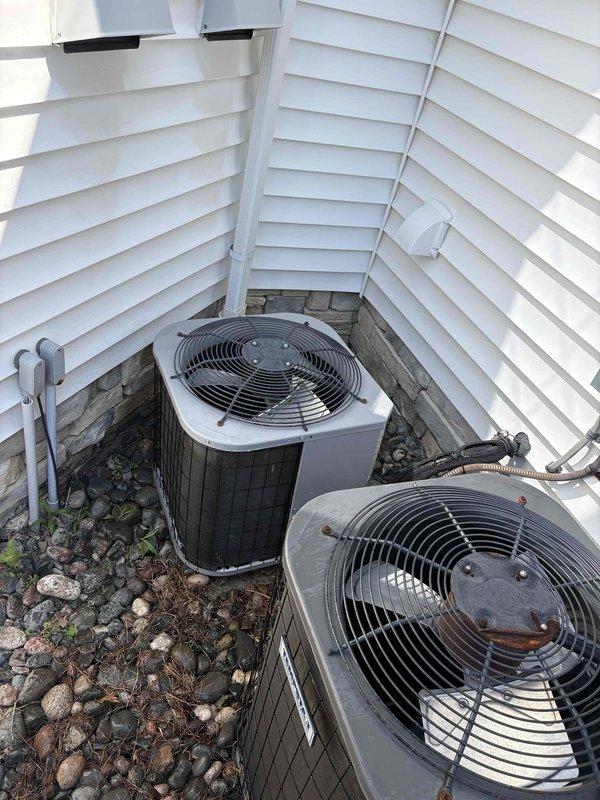 # HVAC Maintenance Summary

Completed routine preventive maintenance on residential split-system air conditioning equipment. Serviced dual outdoor condensing units located in exterior alcove area with adequate clearance for airflow and service access.

# Work Performed

Performed comprehensive cooling system inspection and maintenance on both outdoor condensing units. Conducted visual assessment of equipment condition, noting surface wear and weathering on primary unit while secondary unit showed cleaner appearance. Inspected fan assemblies and protective grilles for proper operation and structural integrity.

Examined electrical components including disconnect box and associated conduit connections. Verified proper mounting and secure installation of electrical service equipment. Checked refrigerant line insulation and flexible conduit connections for signs of deterioration or damage.

Assessed equipment installation platform constructed of composite decking material and treated lumbe