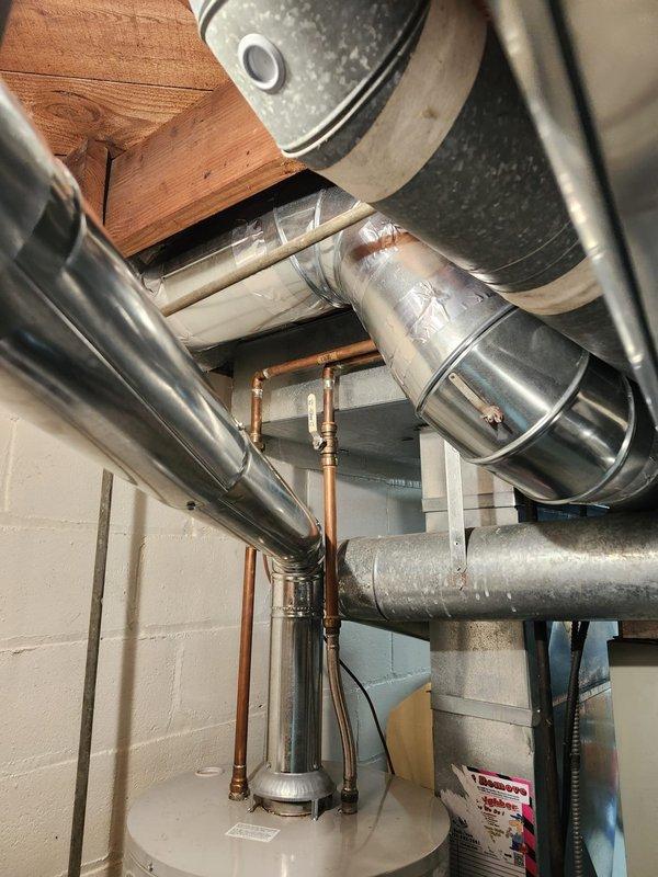 Installed new chimney liner system with two heat runs in basement mechanical room. Routed and secured metallic ductwork connecting to existing furnace unit, ensuring proper clearances from water heater and other utilities. All connections sealed and fastened per manufacturer specifications for safe operation of heating system.