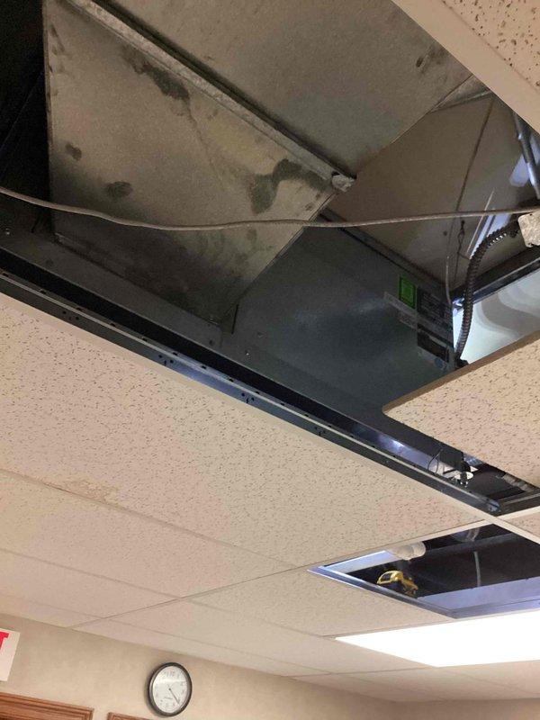 Responded to service call for overheating compressor on commercial air conditioning system. Upon arrival, accessed HVAC control panel and performed diagnostic inspection of electrical components and control board. Verified proper LED indicator status and examined wiring connections, transformer, and relay components for signs of electrical issues or heat damage. Inspected ceiling-mounted air handling equipment in plenum space above drop ceiling to assess compressor condition and related mechanical systems. Documented equipment condition with photos for service records.