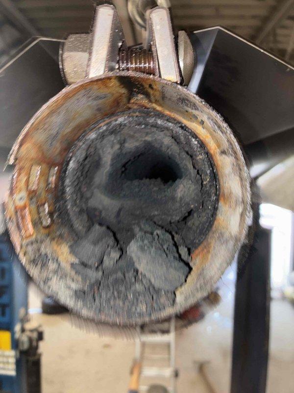 Performed comprehensive cleaning of heavily soiled heat exchanger tubes showing significant soot, debris, and corrosion buildup that was restricting proper airflow and combustion efficiency. Removed existing deteriorated exhaust venting system and installed new B-vent exhaust piping to ensure safe and code-compliant venting of combustion gases from the commercial HVAC unit.