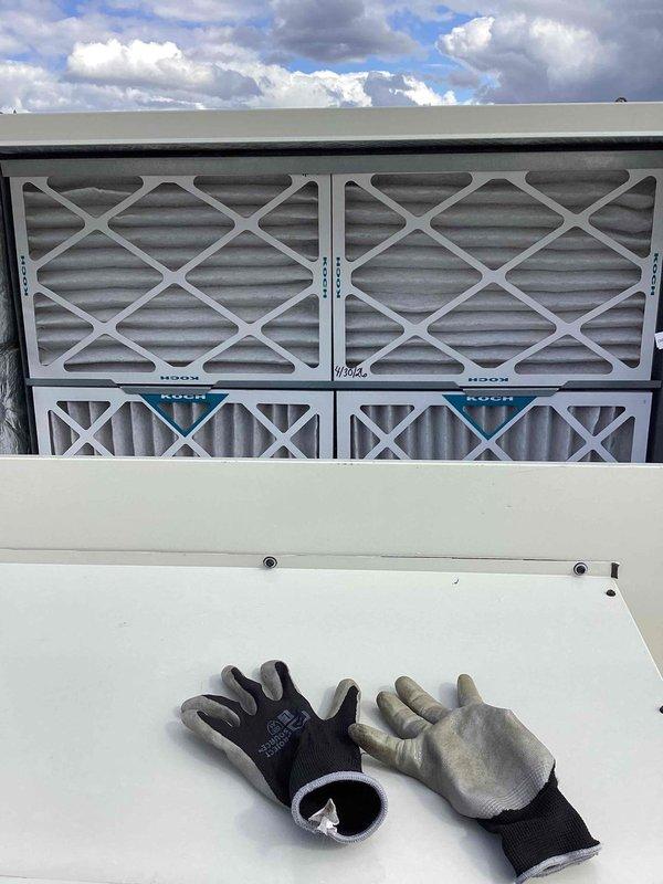 Performed comprehensive clean and check service on commercial rooftop HVAC unit. Inspected evaporative cooling system with diamond-pattern grille and verified proper operation of all mechanical components including fan assembly and refrigerant lines. Replaced four air filters in the intake housing—two larger upper filters and two smaller lower filters—ensuring proper airflow and system efficiency. Cleaned exterior surfaces, checked electrical connections, and confirmed all copper piping connections were secure with no visible leaks or damage.