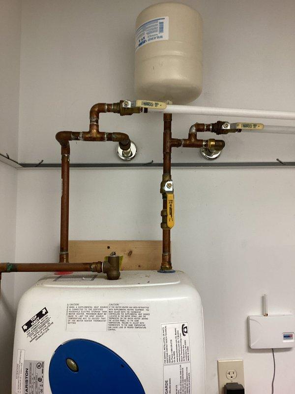 Conducted on-site evaluation of existing water heater system for replacement estimate. Assessed current installation including white tank-style water heater with expansion tank, copper supply piping with multiple shut-off valves, and PVC venting configuration. Documented existing plumbing connections, electrical requirements, valve placements, and overall system condition. Photographed installation setup to provide accurate replacement specifications and pricing options for new water heater unit.