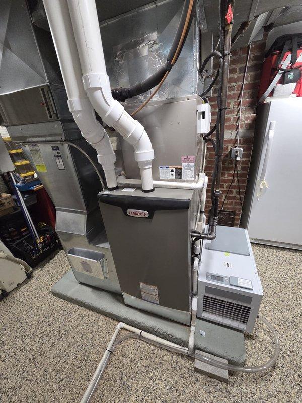 Completed furnace retrofit installation in basement mechanical room. Installed new Lennox furnace unit with proper PVC venting routed through ceiling, connected to existing ductwork system, and integrated with supplemental HVAC equipment including air handler and dehumidification unit. All gas lines, electrical connections, and copper piping secured to brick wall per code requirements, with system tested and operational upon completion.