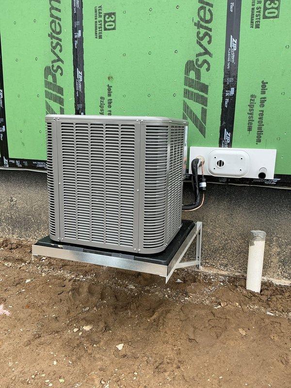 Completed new construction HVAC installation including outdoor condensing unit (Model ML17KC2-048-230A02) mounted on elevated metal platform stand with proper electrical disconnect and conduit installation. Unit installed against ZIP System insulated exterior wall with 30 feet of refrigerant line set charged and ready for system startup upon completion of construction phase.
