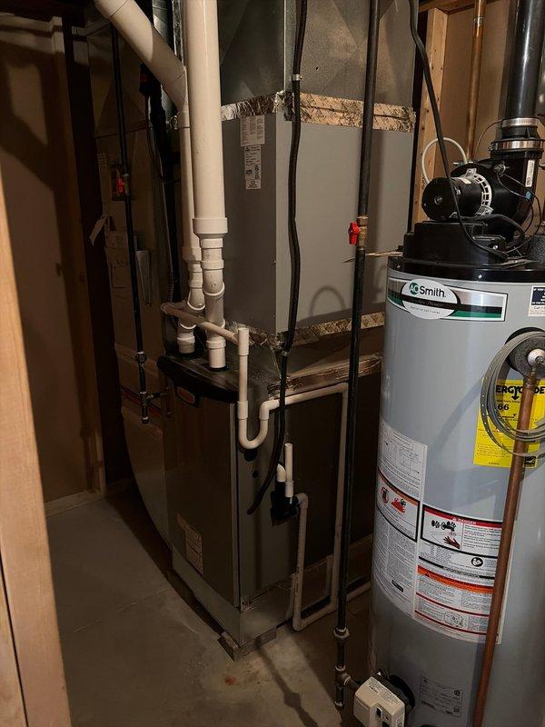 Completed full furnace replacement in basement utility area. Removed existing unit and installed new furnace system with proper venting configuration using white PVC intake and exhaust piping. Connected all necessary gas lines, electrical connections, and integrated system with existing A.O. Smith water heater. Installed exterior termination components including PVC vent pipes through wall with proper flashing and support brackets. Verified all connections for proper operation, tested system startup sequence, and confirmed adequate airflow and combustion performance. Unit operating within manufacturer specifications.