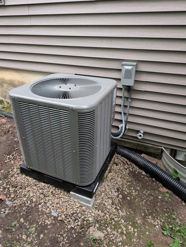 Completed AC retrofit installation at residential property. Removed existing HVAC equipment and installed new air conditioning condenser unit with matching evaporator coil system. Positioned condenser on equipment pad against exterior wall with proper clearances, installed electrical disconnect box with conduit connections, and ran refrigerant line set between outdoor and indoor components. Verified proper drainage routing, tested system operation, and confirmed all electrical connections meet code requirements.