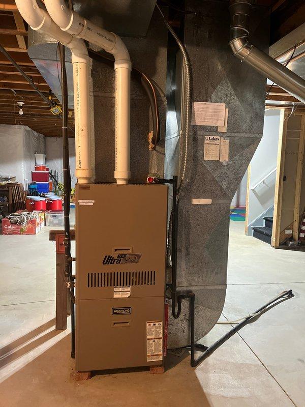 Completed full HVAC system retrofit in residential basement, installing new Ultra-branded high-efficiency furnace with PVC venting system and matching outdoor condensing unit. Installed furnace with proper metallic flex ductwork connections to existing plenum, routed PVC exhaust and intake piping through basement ceiling, and positioned new outdoor AC unit on prepared mulch bed with appropriate refrigerant lines and electrical disconnect. All components installed to manufacturer specifications with proper clearances and code-compliant configurations.