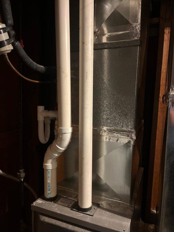 Completed AC retrofit installation in residential basement utility area. Installed new HVAC system including air handler unit with associated condensate drain lines using white PVC piping, properly secured and routed through existing structure. Connected metallic ductwork with sealed seams and reflective tape to ensure proper airflow and system efficiency. All components installed per manufacturer specifications with proper clearances and support.