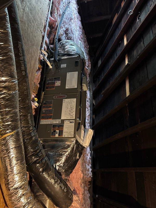 # HVAC System Replacement

Completed full HVAC system replacement including outdoor condensing unit and indoor air handler. Removed existing equipment and installed new Coleman air handler in attic space between floor joists with proper clearances maintained. Configured unit horizontally to accommodate confined installation area. Connected flexible insulated ductwork to air handler with metallic outer layer for optimal airflow distribution. Established all electrical connections and wiring to unit per manufacturer specifications. Verified proper placement on plywood decking with adequate structural support. Ensured all manufacturer labels and specification plates remained visible and accessible for future reference. Installed outdoor condensing unit on exterior of building adjacent to vinyl siding. Routed refrigerant lines and electrical connections between indoor and outdoor components. System tested and confirmed operational upon completion.