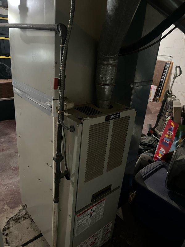 Conducted comprehensive assessment of existing residential HVAC system for complete furnace and air conditioning replacement. Evaluated current forced-air heating system with beige cabinet furnace unit installed in basement utility area, including existing ductwork configuration and connections. Assessed outdoor air conditioning unit placement relative to patio area and determined requirements for relocation to improve aesthetics and functionality. Documented existing equipment specifications, ductwork routing through cylindrical supply ducts, and current mechanical room layout including water heater proximity and available space constraints. Provided detailed retrofit estimate for new furnace and AC system installation with outdoor unit repositioning away from patio area per customer request.