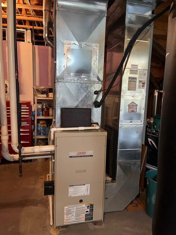 Completed full HVAC system retrofit in residential basement, replacing existing furnace and air conditioning equipment. Installed new Lennox furnace unit with proper connection to existing ductwork system including pyramidal plenum and galvanized metal distribution runs. Exterior installation included new air conditioning condenser unit positioned on decorative rock bed with proper electrical disconnect box and conduit routing along house exterior. Verified all refrigerant line connections, electrical components, and system controls for proper operation upon completion.