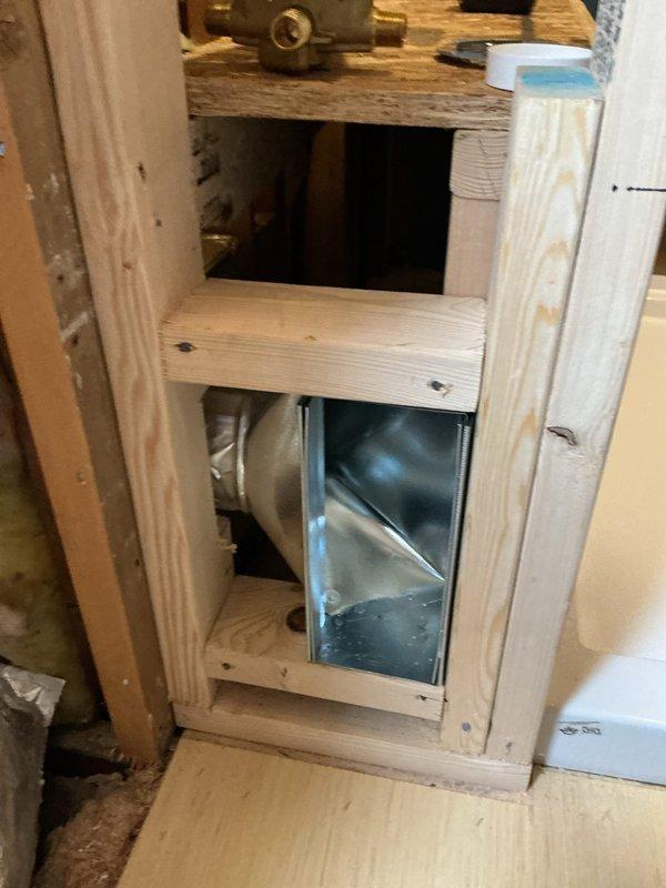Completed HVAC rough-in installation for master bathroom ductwork. Installed metallic transition boot and flexible duct connection within wooden wall framing to facilitate proper airflow to the space. Positioned ductwork components to accommodate existing plumbing fixtures and ensure adequate clearance for final drywall installation.