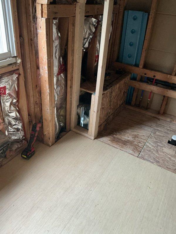 Completed HVAC rough-in installation for master bathroom ductwork. Installed metallic transition boot and flexible duct connection within wooden wall framing to facilitate proper airflow to the space. Positioned ductwork components to accommodate existing plumbing fixtures and ensure adequate clearance for final drywall installation.