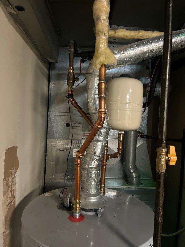 Completed full HVAC system replacement including outdoor condensing unit and indoor water heater. Installed new air conditioning condenser on gravel pad against building foundation with proper condensate drainage via PVC piping, and replaced water heater in utility closet with new unit featuring copper piping, brass fittings, pressure relief valve assembly, and expansion tank. All components properly connected, tested, and verified operational.