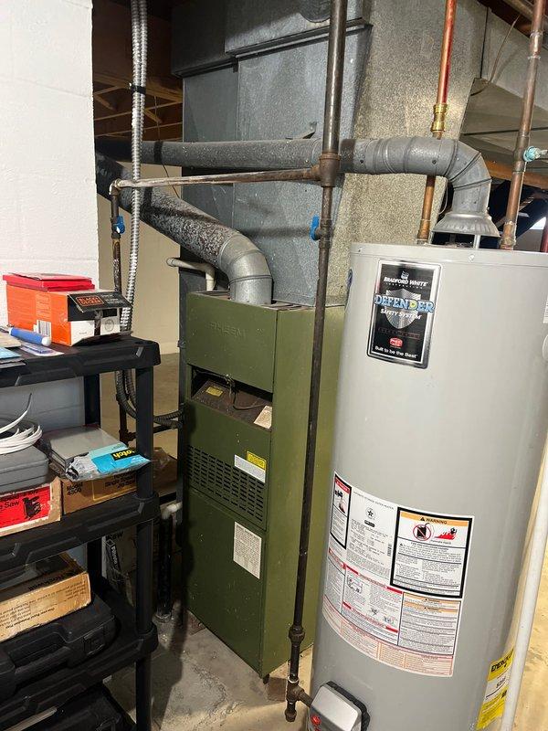 Conducted comprehensive assessment of existing HVAC system for replacement estimate. Evaluated indoor furnace unit and outdoor condensing unit, documenting current equipment configuration, ductwork connections, electrical service, and installation conditions. Photographed basement utility area showing green furnace with adjacent water heater and metal duct system, as well as exterior condensing unit with electrical disconnect and proper placement on concrete pad. Provided detailed replacement options and specifications based on current system layout and customer requirements.