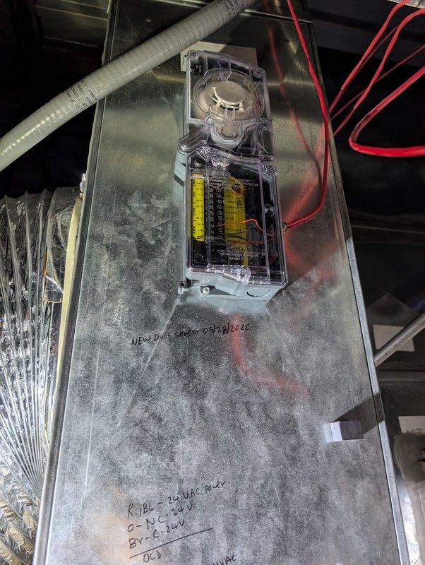 Installed new duct smoke detector on commercial HVAC air handler unit. Device was mounted to the top cabinet surface with clear protective housing containing internal electrical components, motor assembly, and proper wiring connections. Unit tested and operational upon completion.