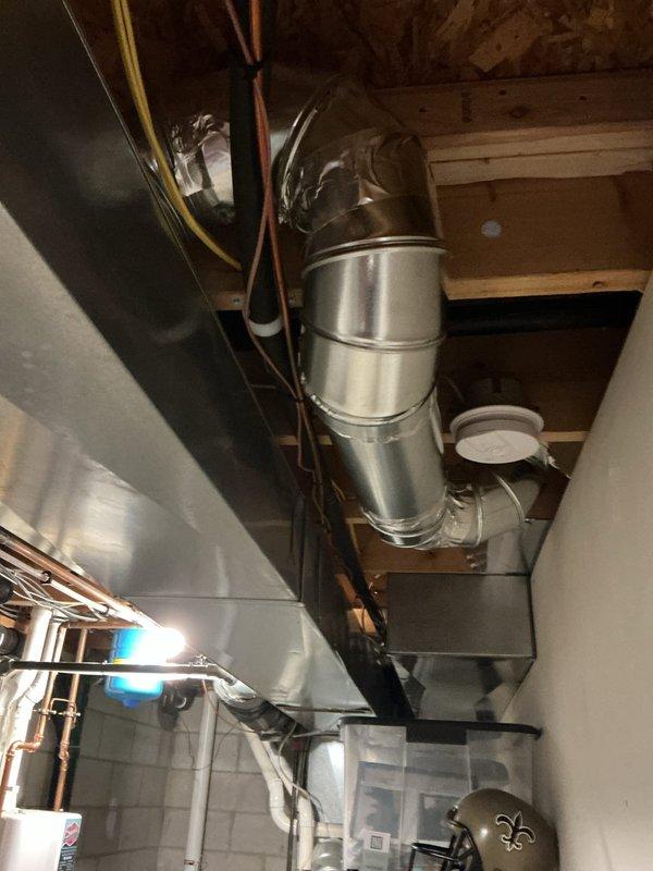 Completed installation of ductwork for master bathroom in new construction project. Installed stainless steel duct runs with elbow joints and rectangular plenum connection, routing through basement ceiling joists to serve bathroom area. Left two registers on site as requested for final installation phase.